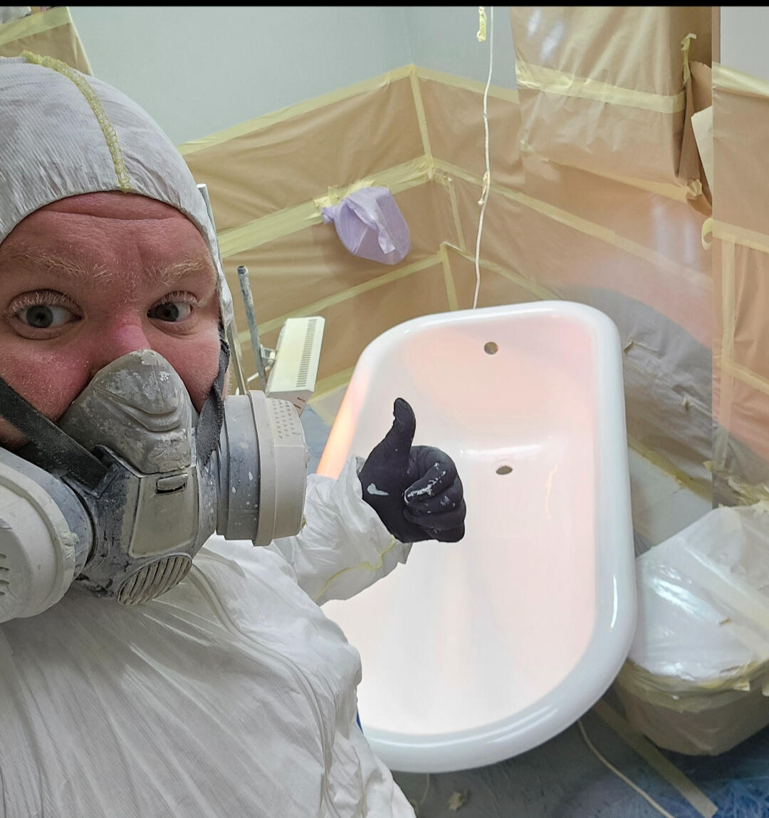 photo of glossy baths owner photo of glossy baths re-enamelling owner Seamus with a thumbs up, in ppe, in a room full of masking up and a completed bath in Newport